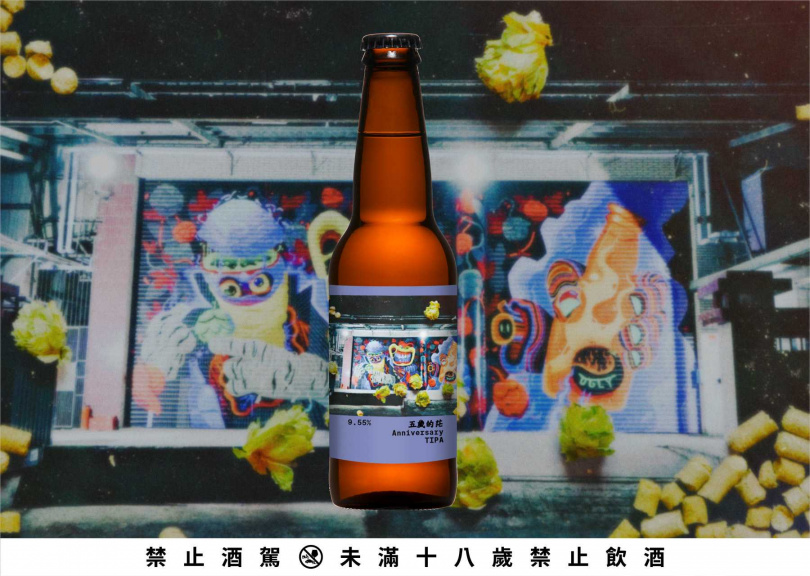 「五歲的茫 Anniversary TIPA」酒標可見夜晚打燈下有著塗鴉的酉鬼酒廠大門，飄散落下的啤酒花則是啤酒廠的靈魂要角。（圖／酉鬼啤酒提供）