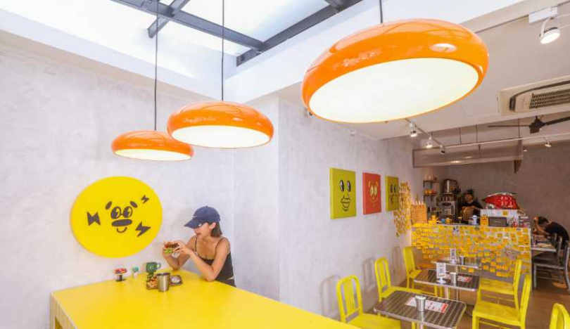 店內以鮮明的黃、橘色營造視覺亮點，牆上笑臉Logo是許多客人最愛的打卡背景。（圖／趙文彬攝）