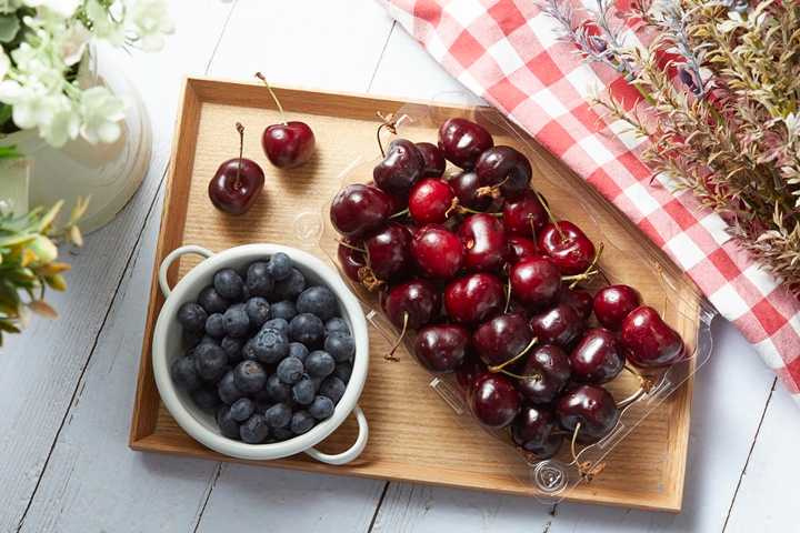 來自美國百年農場Naturipe Farms的藍莓(左)，果粒大小超過1.2公分以上，以人工進行採收的美國西北大櫻桃(右)渾圓飽滿，是當季必買。