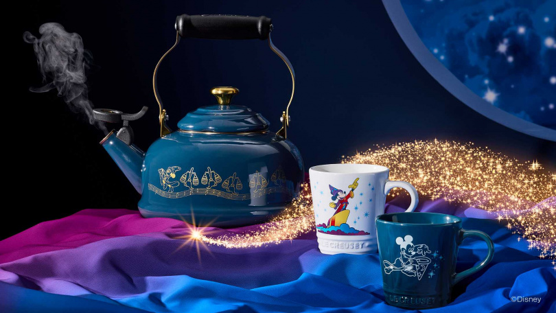 Le Creuset【Fantasia 魔法師米奇系列】琺瑯琴音壺與 V 馬克杯，同樣以夜謐藍與雪花白呼應主題。當水滾沸、壺口響起笛音的瞬間，如同樂章開場的序曲；不論是晨間的咖啡香或午後的暖茶時光，皆能為日常注入柔和而暖心的魔力。（圖片提供／LE CREUSET）