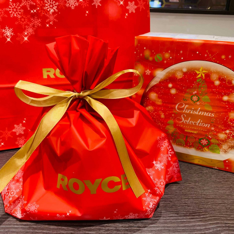 提供免費聖誕限定包裝服務，有著印滿白色靄靄雪花的紅色聖誕包裝袋，並搭配燙金ROYCE’字樣的金燦緞帶。（圖／ROYCE’提供）