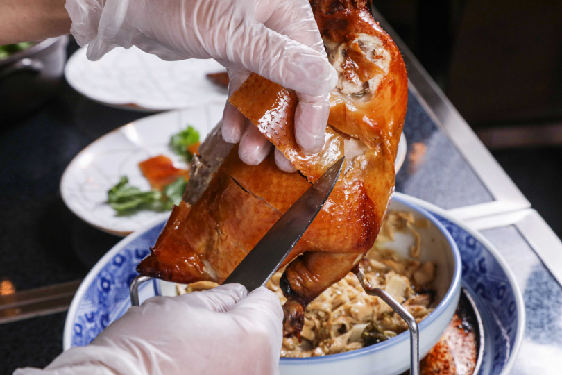 掛爐燒雞會在桌邊進行片皮、分肉動作，不時可見雞汁流入底下的酸菜與筍絲中。（圖／趙文彬攝）