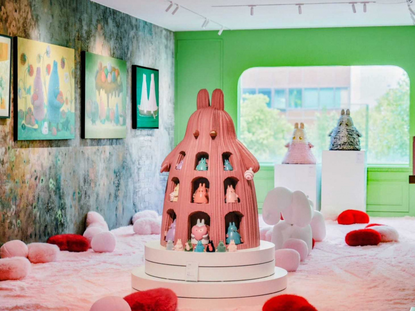 四樓另一翼展區以鮮明飽和的翠綠牆面,搭配林天祿立體Momo兔雕塑形成強烈對比;畫作中划船的場景延伸至空間裝置,虛實交錯的陳列語彙,引領觀者走入溫柔夢境。(圖/光之間 Art Space提供)