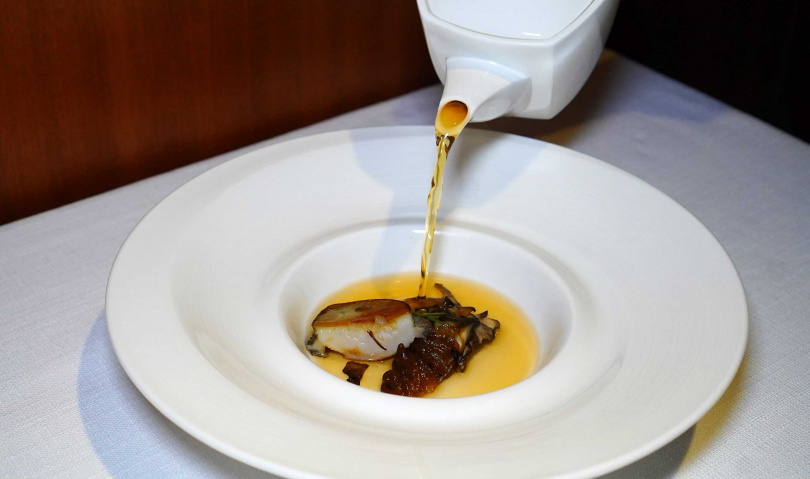 「上湯煨鮑魚海參」上桌後，服務生會在桌邊將熱湯注入裝有溏心鮑魚、軟滑海參和乾煎舞菇的湯盤內，香味沁鼻。（圖／魏妤靜攝）