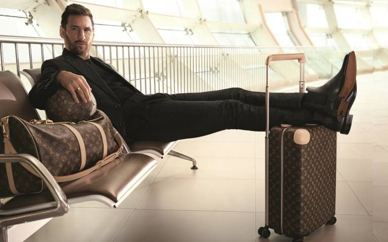 足球球王梅西被捕獲機場帥氣登機形象，穿全黑西裝拉LV  Horizon行李箱翹腳擺拍，時髦到爆！
